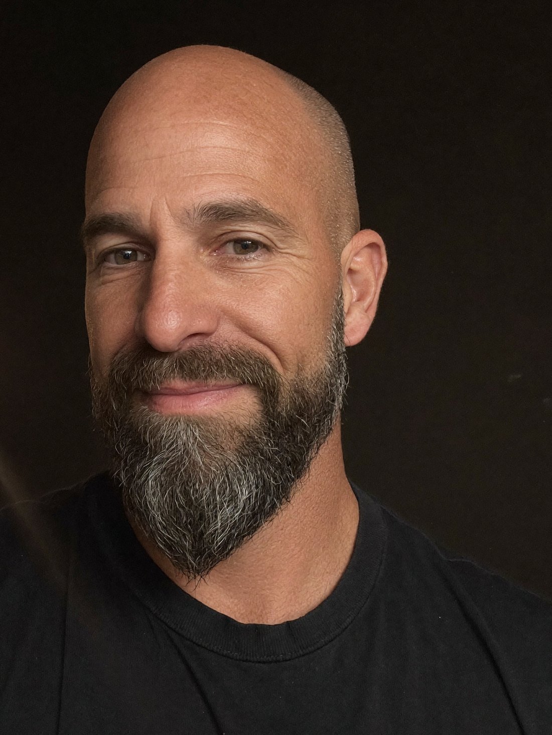 David, who makes BeardedFaces, in a black t-shirt against a dark ground